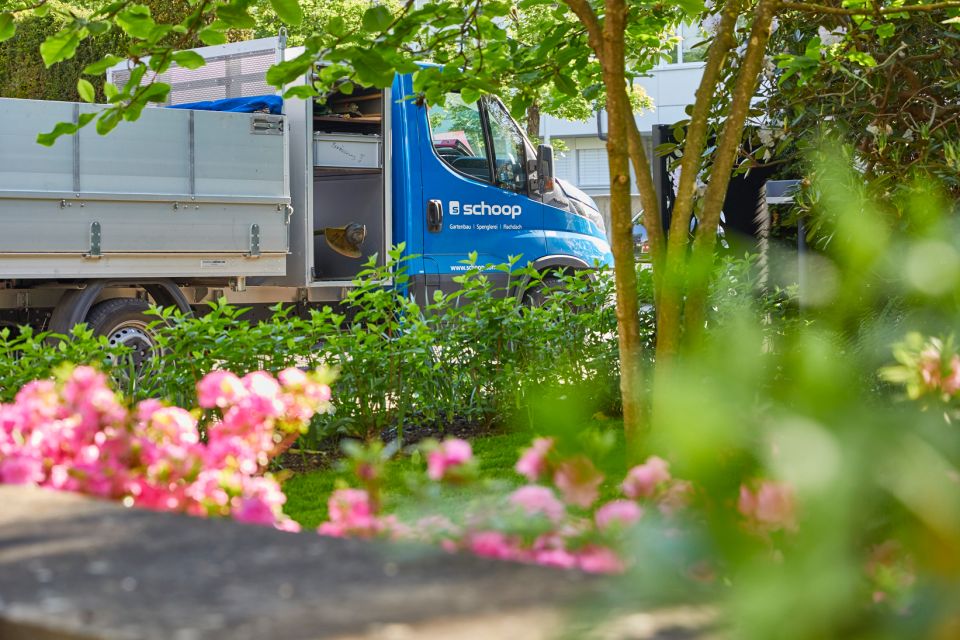 Blauer Schoop Gartenbau Lastwagen bei Gartenpflege mit Blumen und Bäumen im Aargau